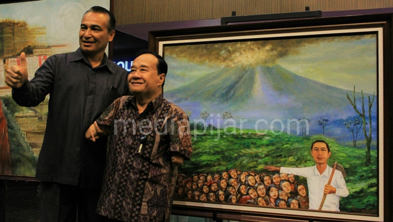 Sayang Bangun (kanan), berfoto di samping lukisannya yang berjudul Erupsi Gunung Sinabung yang dibanderol dengan harga Rp. 20.000.000,- dalam Pameran Lukisan dan Fotografi: Seniman Peduli Sinabung (8/11) di Gedung Uni Plaza, Medan.
